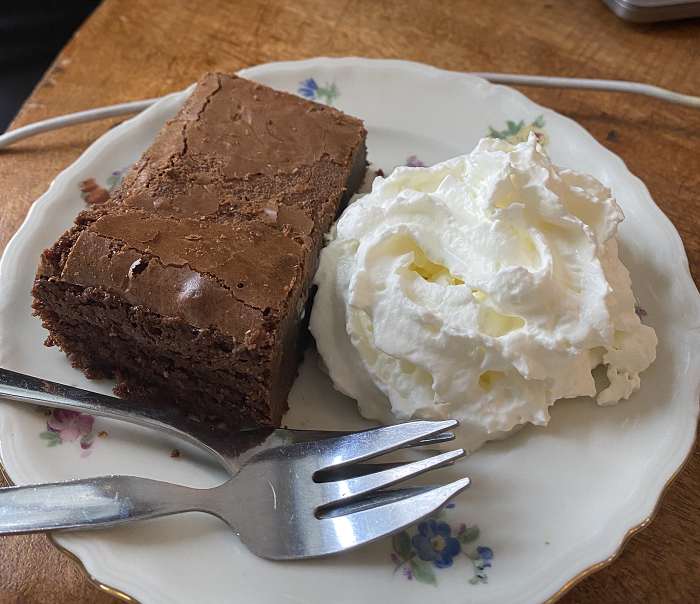 A small plate with a brownie on the left and whipped cream on the right. 
