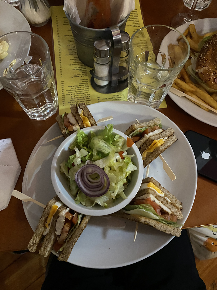 A large plate with a sandwich sectioned into four slices and a side salad in the center. 