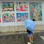 girl with umbrella in front of wall art