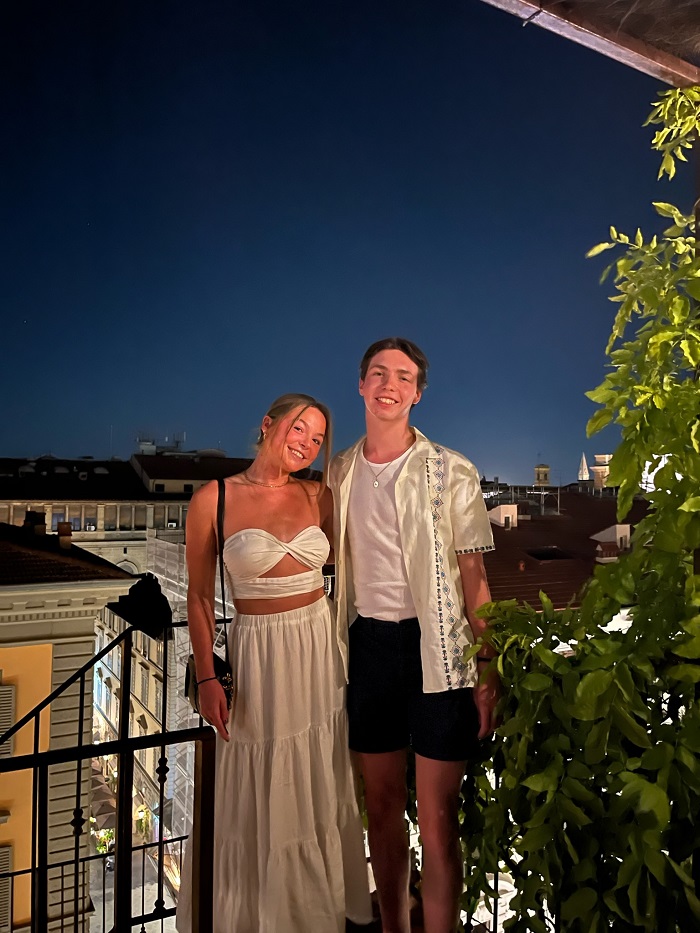 two frineds standing on balcony at night