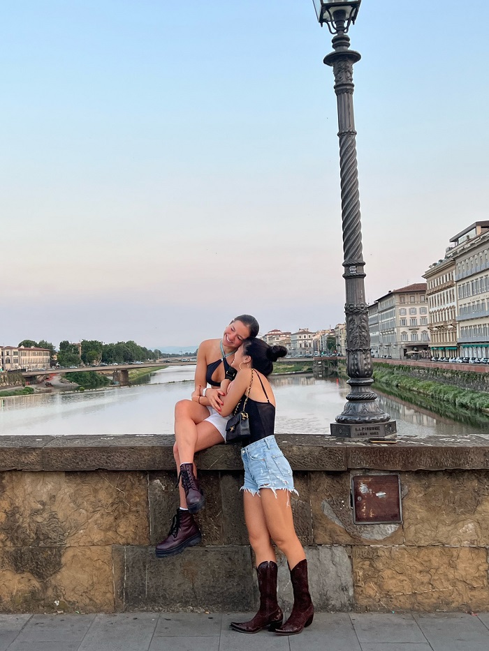 Two friends sitting on bridge in front of river
