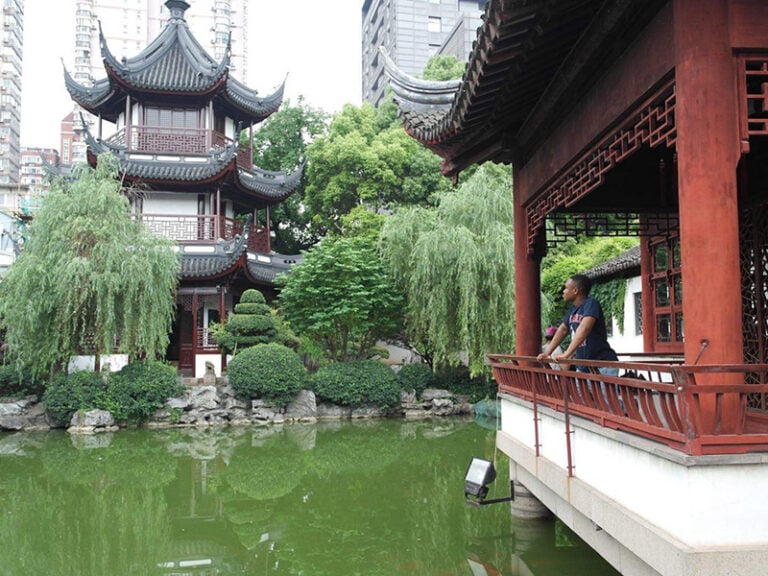 Study abroad student wearing Howard University t-shirt looks out at a pond in the Yu Yuan Gardens in Shanghai