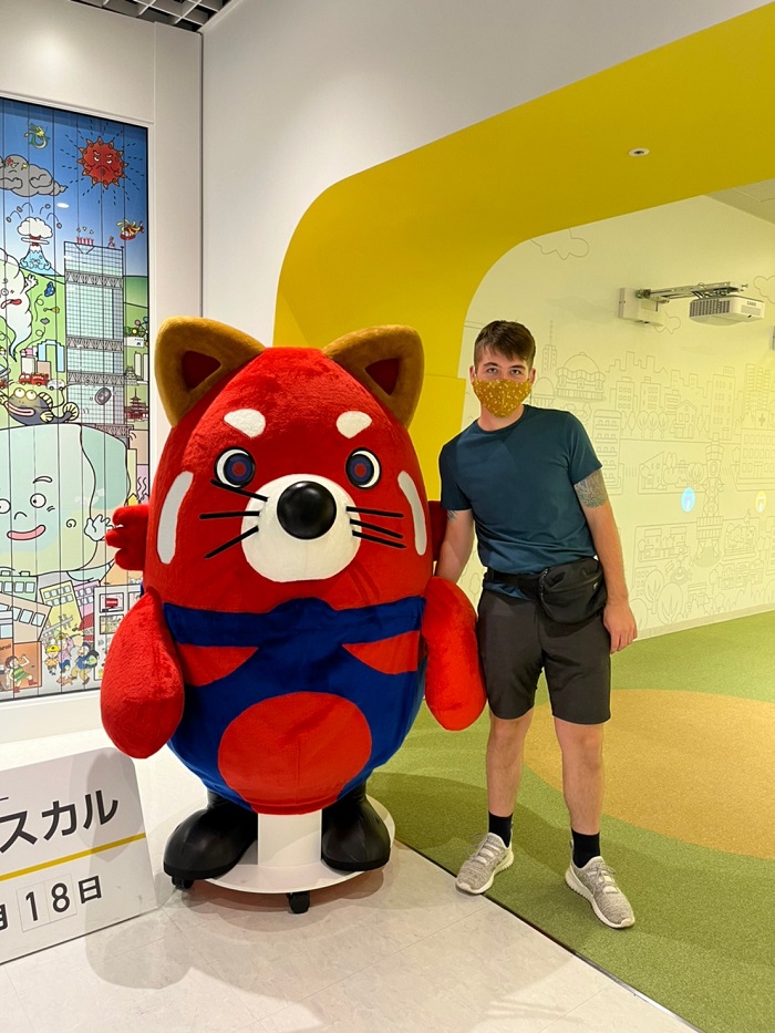 Cody standing next to red animal mascot