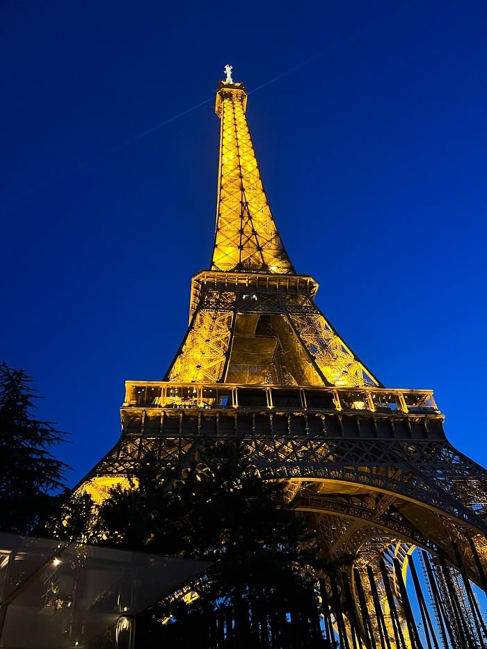 The Eiffel tower lit up yellow at night