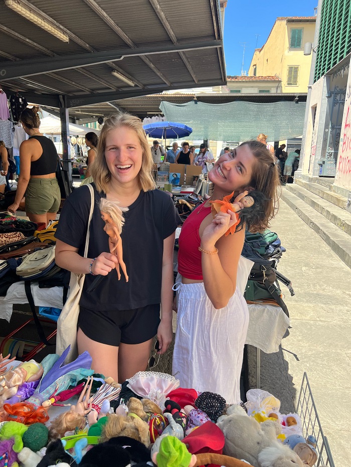 two friends holding dolls at market vendor 