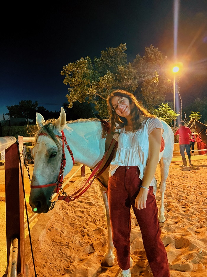 Grace standing with white horse at night