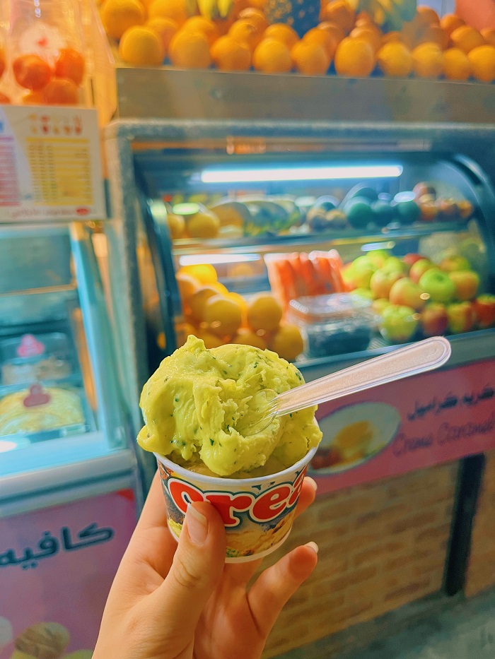 a small cup of green ice cream in front of a stand