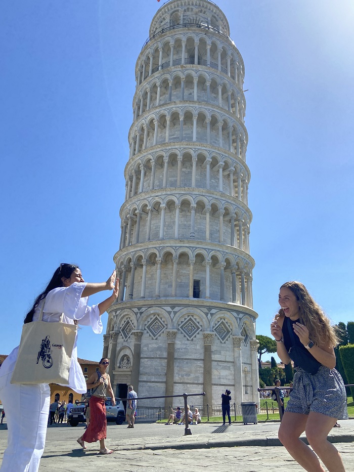 Esme pretending to push the leaning tower of Pisa toward her friend