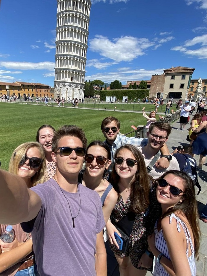 Selfie of sarah and a group og friends in front of the leaning tower of Pisa