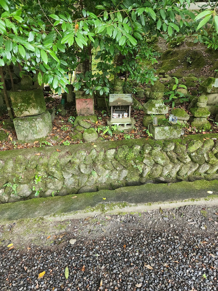 small rocks and small wooden shrine built on side of the road