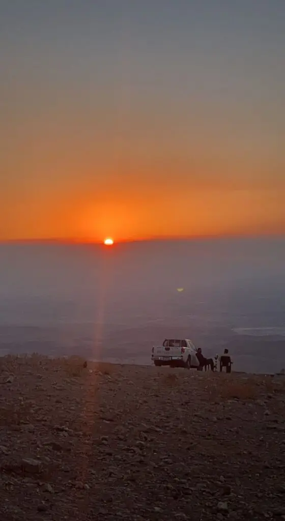 two men sitting next to truck during sunset