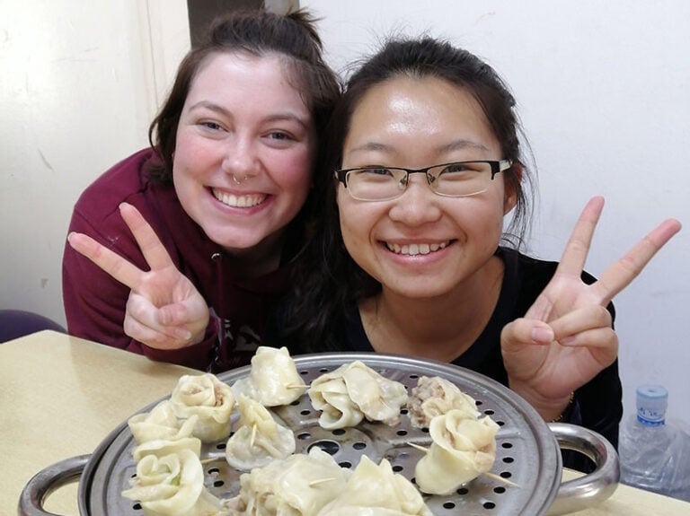 CET Harbin study abroad student and local roommate smile over a tray of dumplings they made