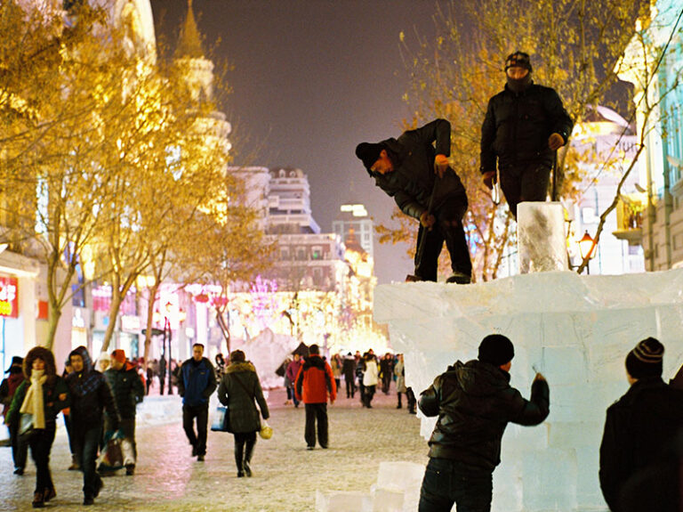 Workers carve a block of ice at the Harbin Ice Festival
