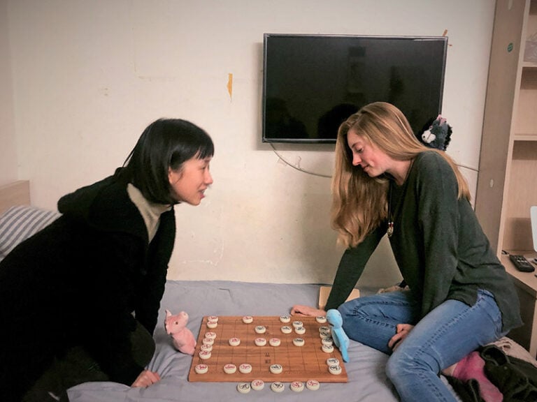 CET Shanghai summer study abroad student and her roommate play a board game in their room