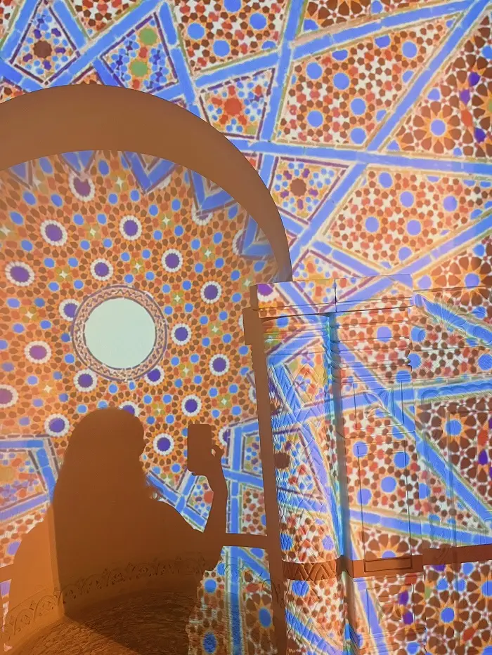 Shadow taking a picture in front of a mosaic wall projection