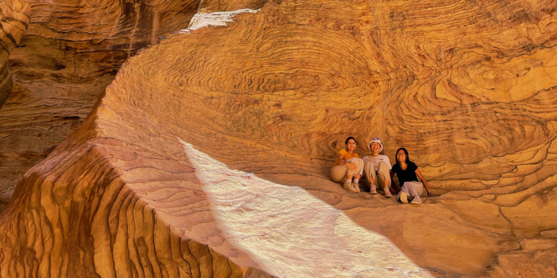 Three CET Jordan students sit in the crevice of a rock face in Wadi Rum