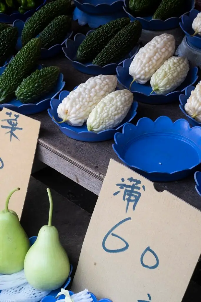 Different types of melon on display in bright blue plates with a cardboard label that reads 60.
