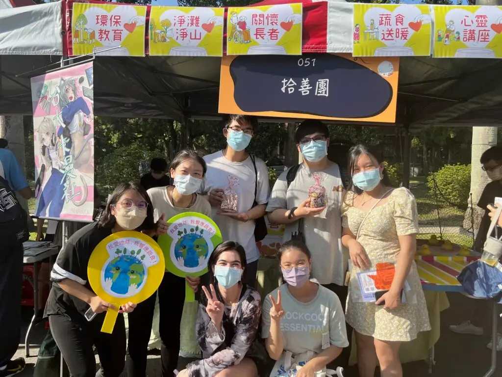 Seven students posing in front of a booth at the university's club fair