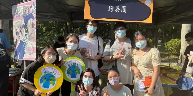 Seven students posing in front of a booth at the university's club fair