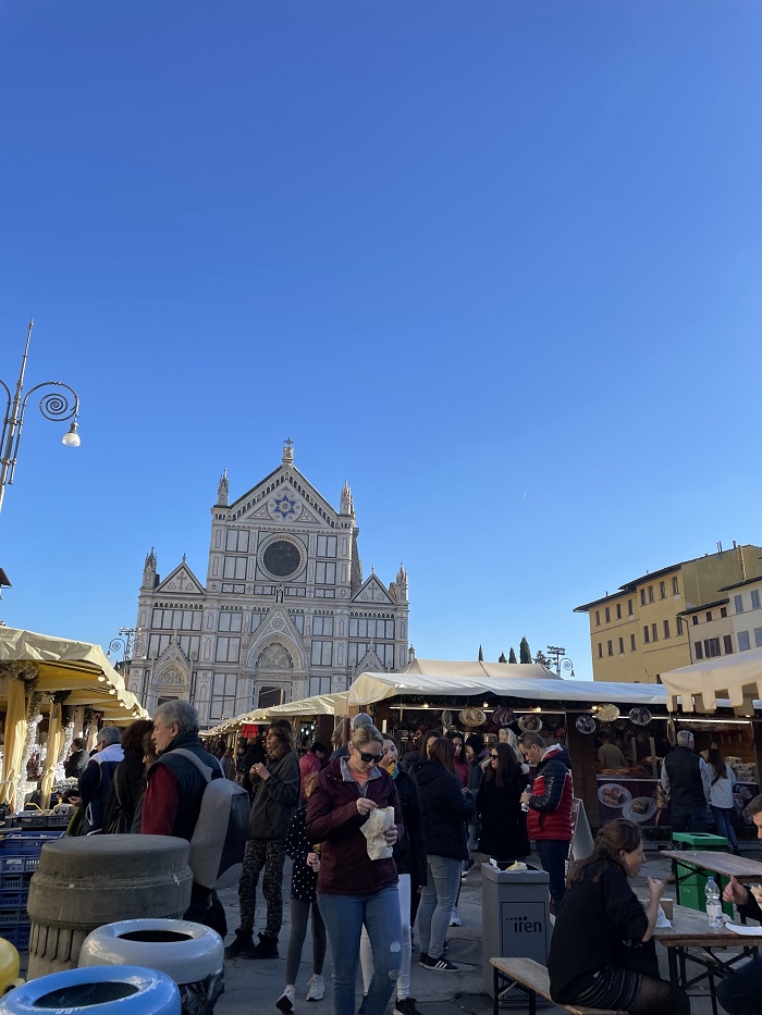 People eating, shopping, and conversing at a christmas market in Santa Croce, Florence