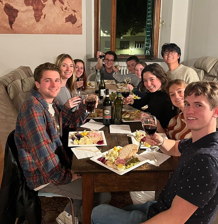 Ten students gathered at a table with plates of thanksgiving food and wine