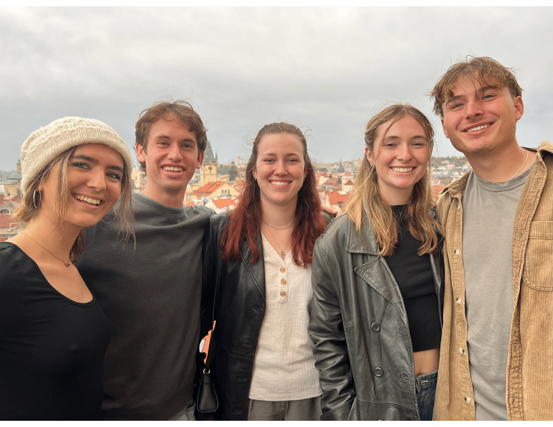 Two male and three female students smiling in Prague