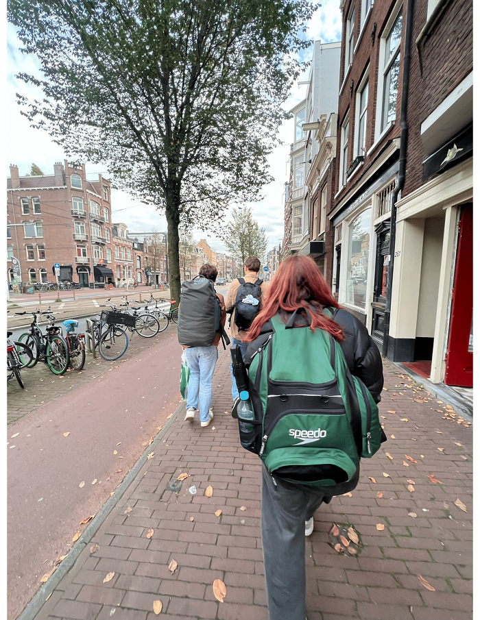 Three students with large backpacks walking on a street
