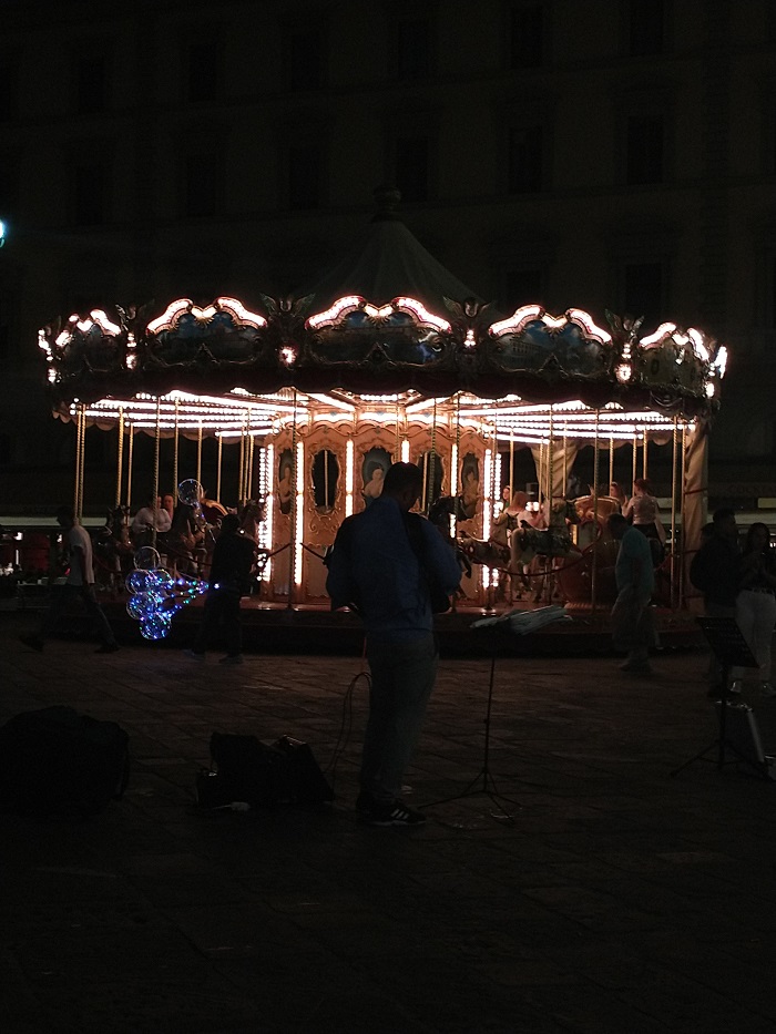 Street musicians playing in front of a carousel at night
