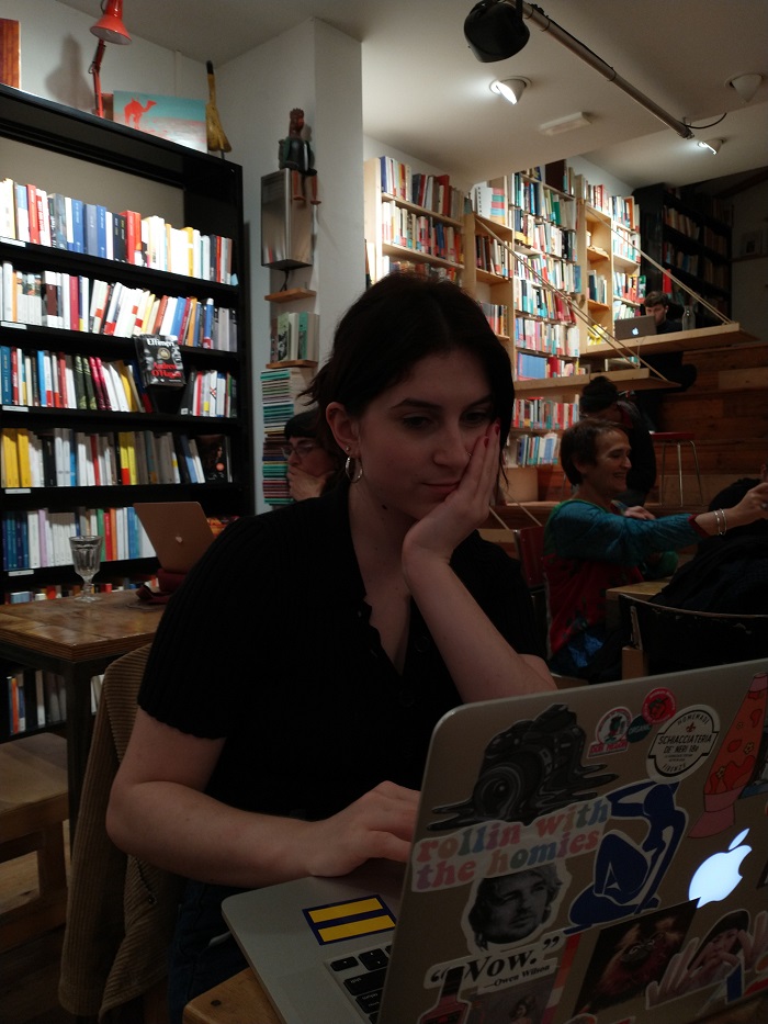 A student working on her computer in a busy coffee shop 
