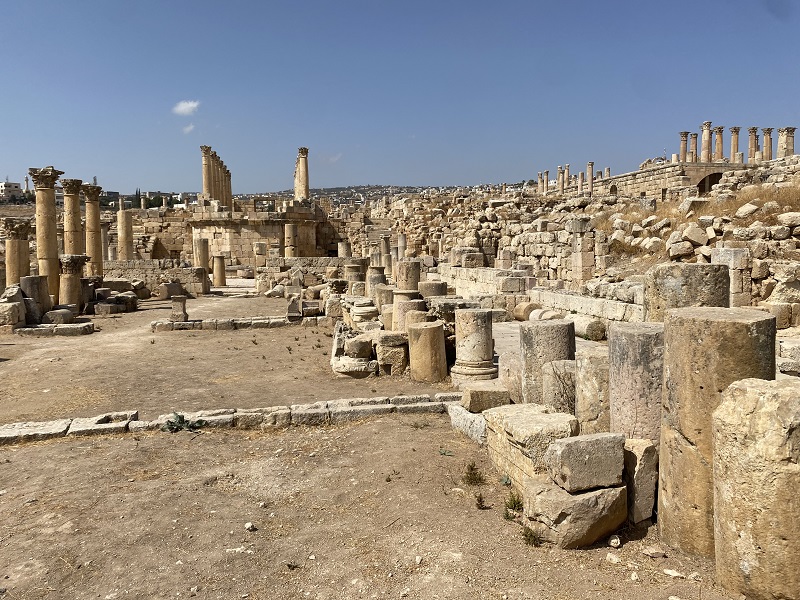 A wide and vast shot of beige colored ruins against a clear blue sky in Jerash.