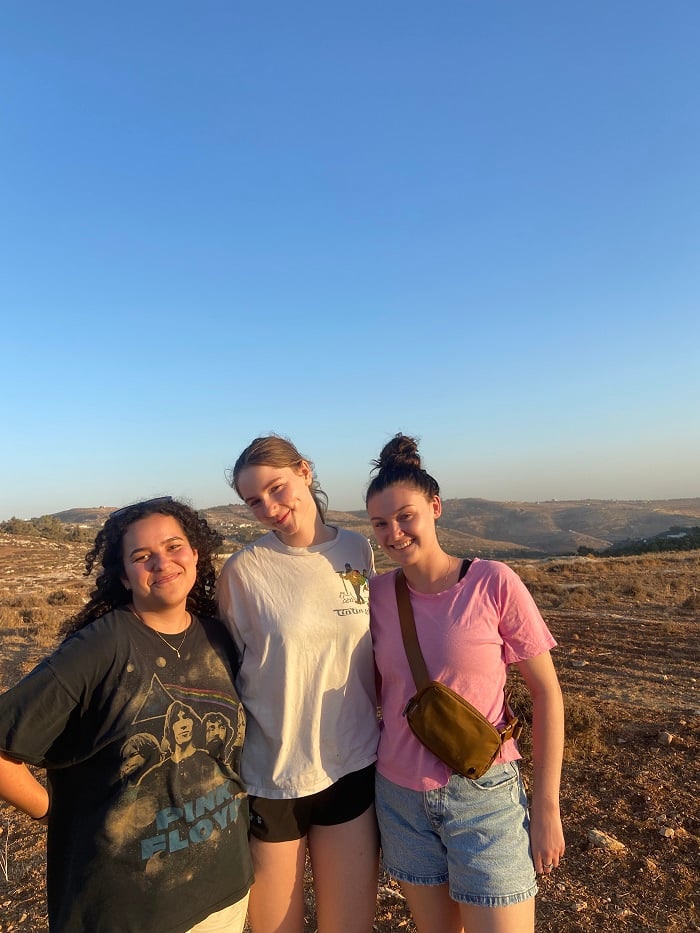 Three female students posing in a bare field in Jordan 