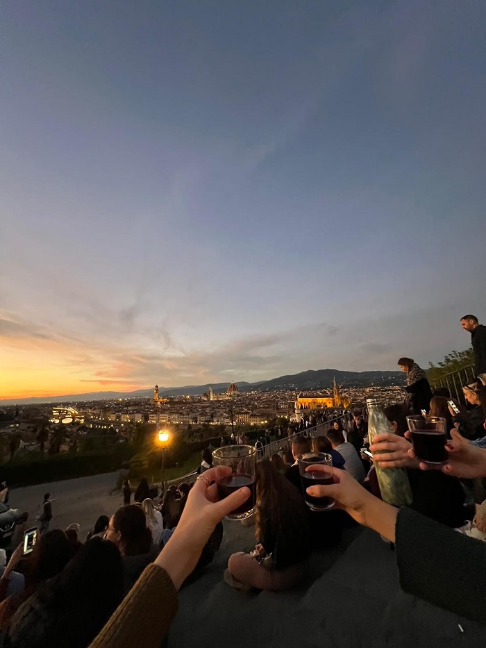 Hands holding wine glasses in front a view of Florence