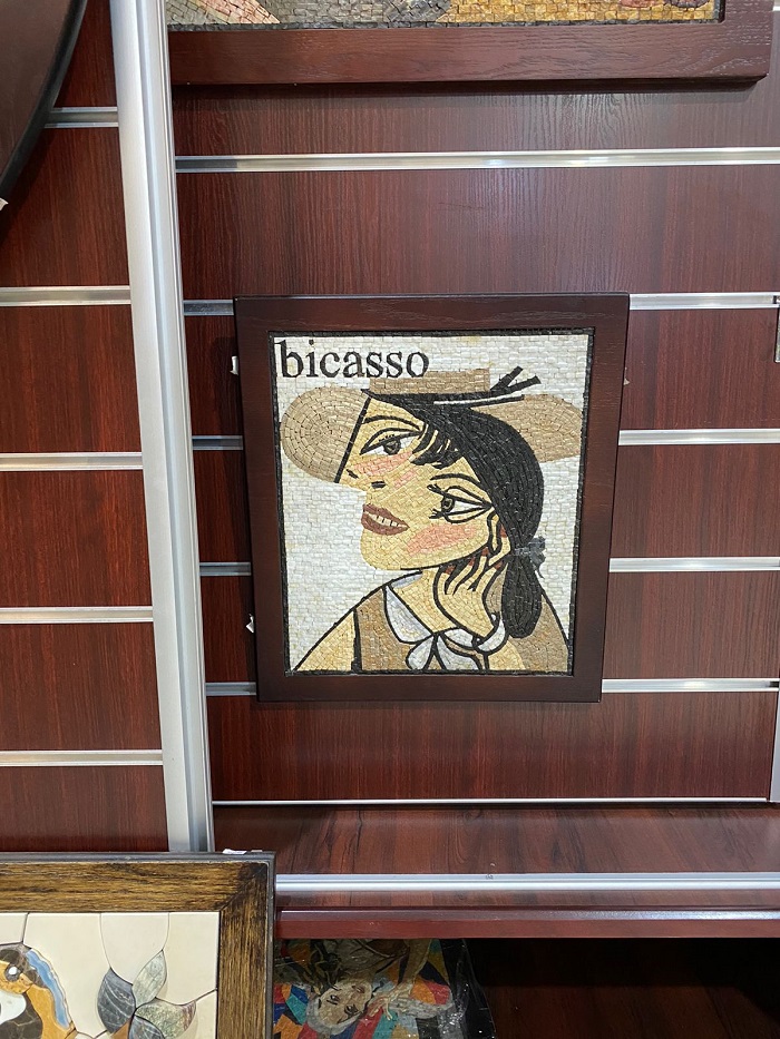 An imitation of Picasso art in a brown frame with the word bicasso on the left top corner and a woman