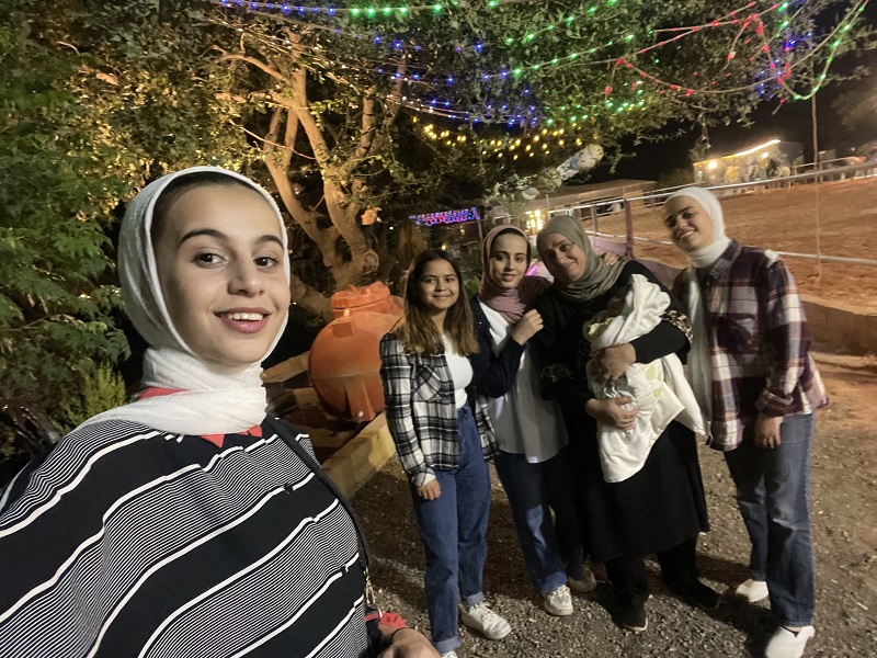 A student and her language partner's family members by a stable in Jordan