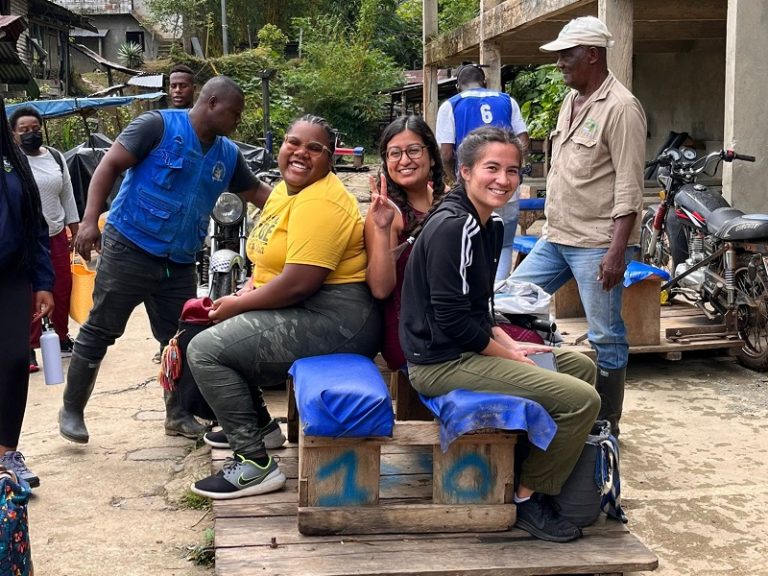 Three students sitting on a railroad cart and smiling for the camera.