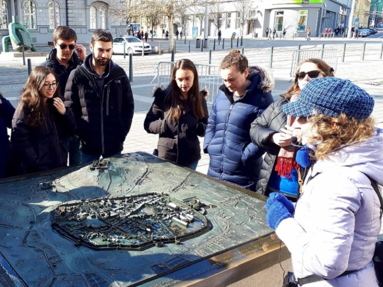 Students around a city model with an instructor on the Traveling Seminar.