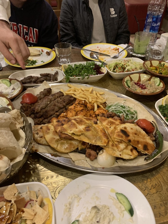 Platters and plates of food including meat, french fries, vegetables and salad from a Jordanian restaurant