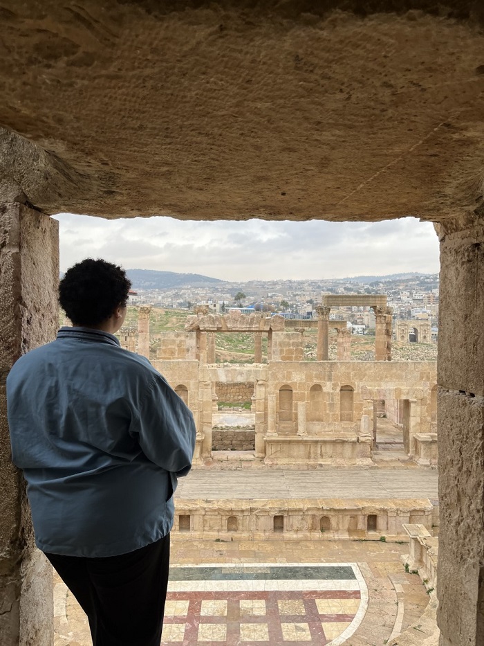 A CET student facing away looking towards one of the theaters at Jerash