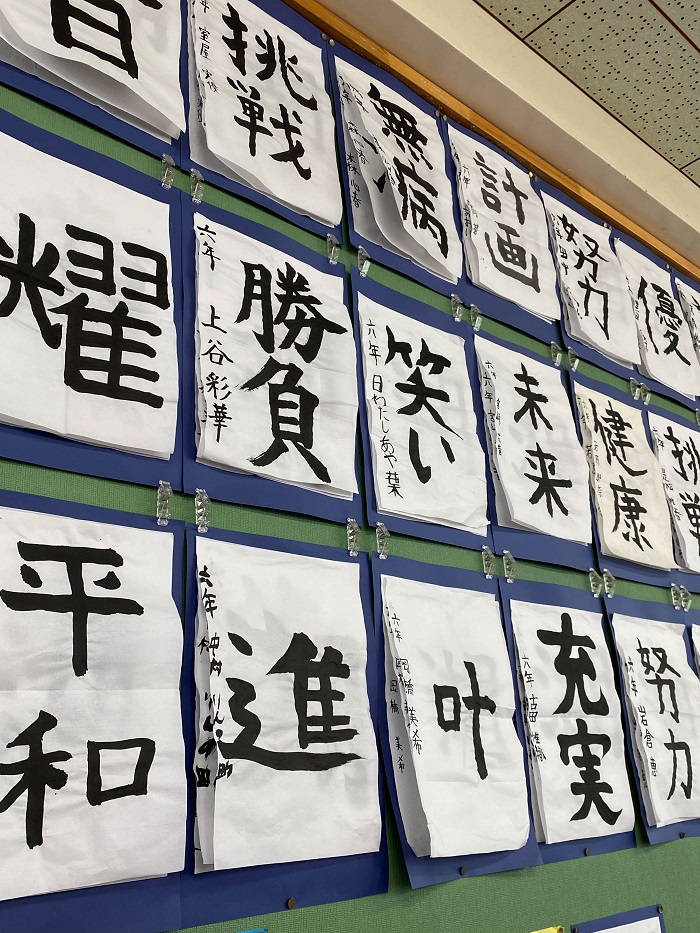 Japanese calligraphy displayed on pieces of paper on a wall in a classroom