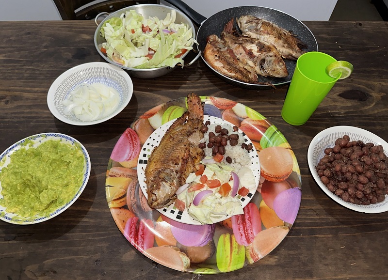 A table with a variety of food including fish, vegetables, and beans