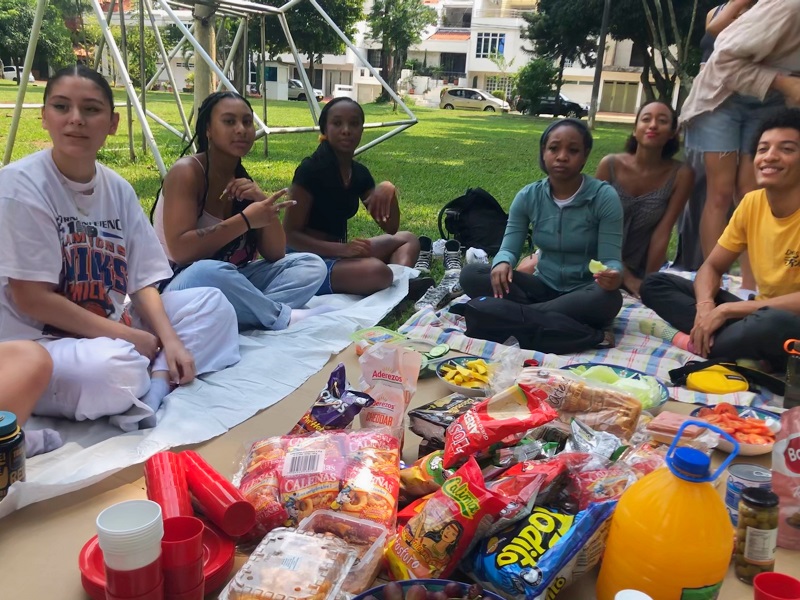 Six students sitting down on a blanket with snacks for a picnic lunch in Colombia