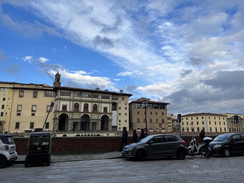 Cars and a Vespa parked along the streets of the Arno River in Florence