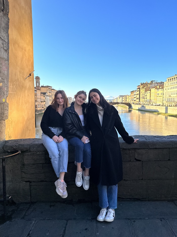Three CET students sitting on a bridge over the Arno River in Florence