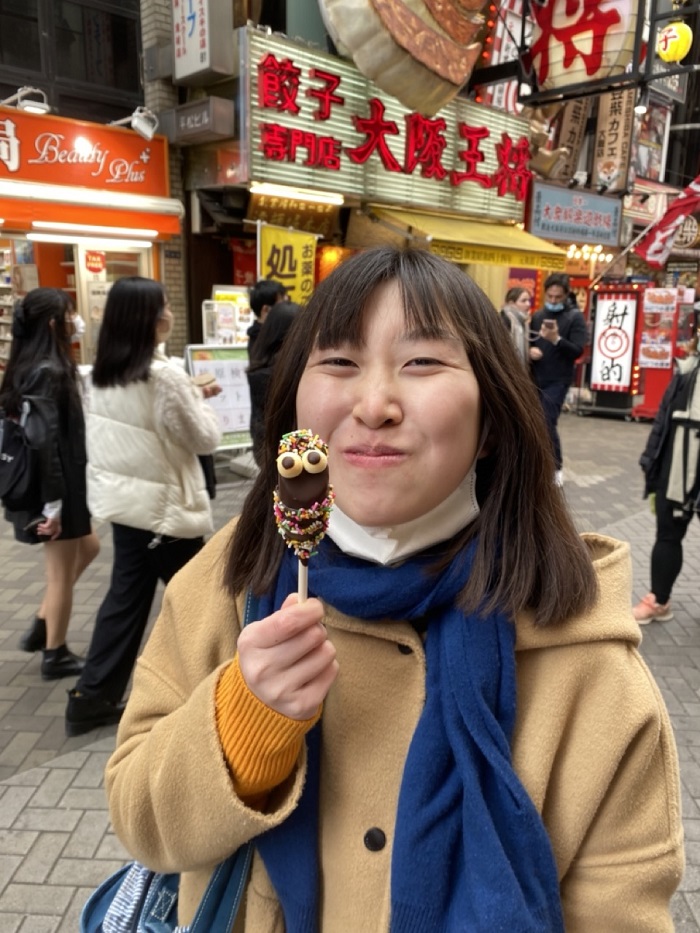 One CET Japan student holding a chocolate covered banana shaped like a bunny in the street of Dotonbori