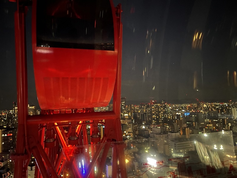 A red ferris wheel cart above the city of Osaka, Japan