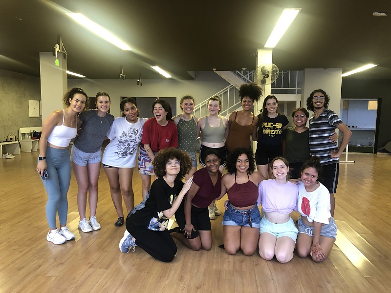 A group of CET students smiling in a dance class with Erika Moura, their dance instructor 