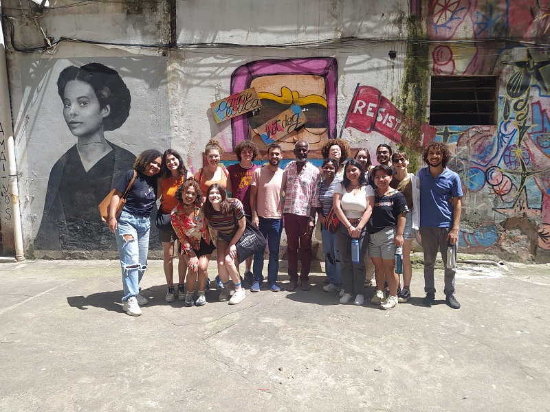 A group of CET Brazil students with the housing movement leader Nelson da Cruz E Souza in front of wall art in São Paulo, Brazil