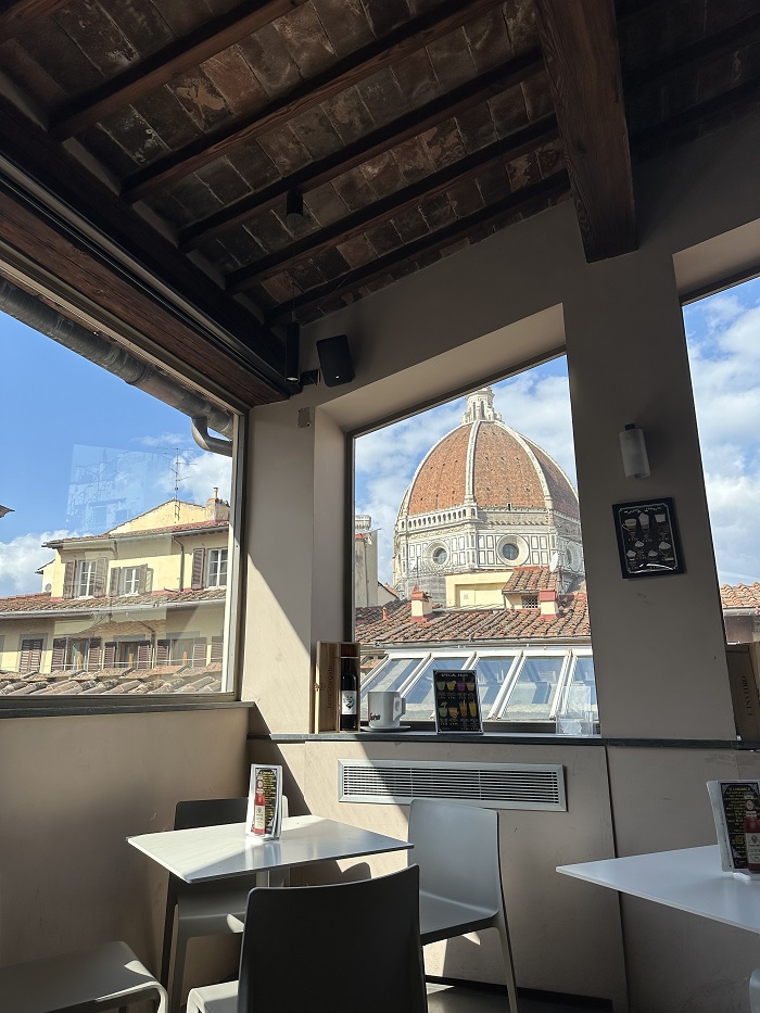 The corner of the inside of a café called Biblioteca Della Oblate with drink menus, tables, chairs and windows   facing the Duomo in Florence, Italy