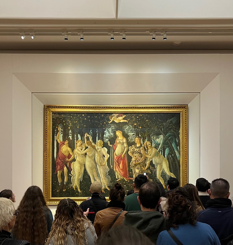 The Primavera art piece centered inside the Uffizi Gallery in Florence, while many people are looking at it