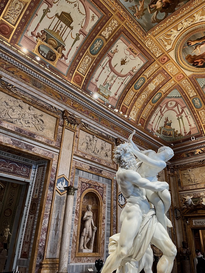 Inside Borghese Gallery with marble statues and intricate walls with fresco paintings
